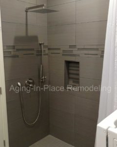 Tile wheelchair accessible shower with ceiling mounted patient transfer lift and wall mounted toilet and walk-in tub.