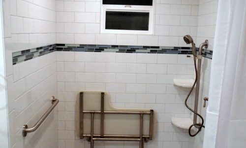 Wheelchair Accessible bathroom remodel with barrier free roll in shower, fold up shower seat, grab bars, hand held shower head, wheelchair accessible roll under sink