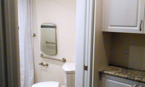 Wheelchair Accessible bathroom remodel with barrier free roll in shower, fold up shower seat, grab bars, hand held shower head, wheelchair accessible roll under sink