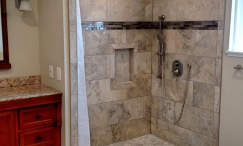 Custom Tile barrier free, roll-in shower with hand held shower head allows for wheelchair accessibility, grab bars for added safety for other bathers