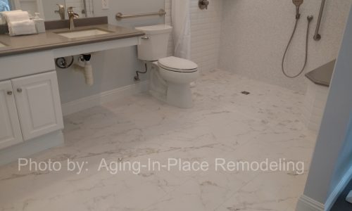 A wheelchair accessible bathroom remodel with roll-in tile shower, with roll under sink, hand held shower head and built in shower bench