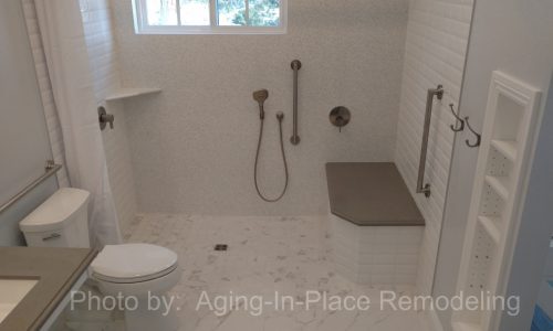 A wheelchair accessible bathroom remodel with roll-in tile shower, with roll under sink, hand held shower head and built in shower bench