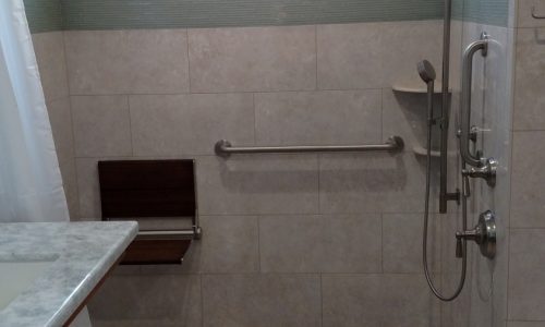 Custom Tile barrier free, roll-in shower with hand held shower head allows for wheelchair accessibility, grab bars for added safety for other bathers