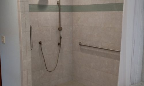 Custom Tile barrier free, roll-in shower with hand held shower head allows for wheelchair accessibility, grab bars for added safety for other bathers