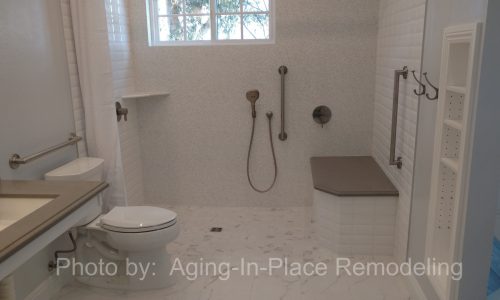 A wheelchair accessible bathroom remodel with roll-in tile shower, with roll under sink, hand held shower head and built in shower bench