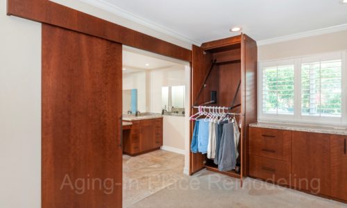 Custom cherry cabinetry, barn doors with one door opening, armoire with automated upper pole