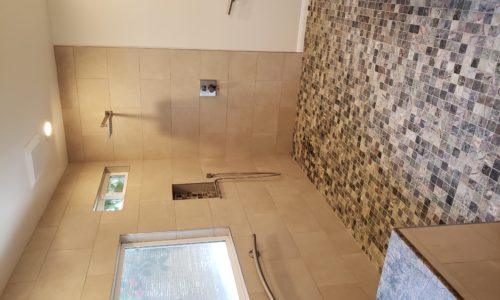 A wheelchair accessible bathroom including a custom tile barrier free shower, curved designer grab bars, built-in shower bench, roll under sink, hand held shower head and bidet toilet