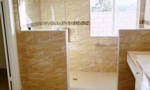 Wheelchair accessible bathroom remodel includes custom tile barrier free shower with built in bench, grab bars, hand held shower head, The vanity is wheelchair accessible.