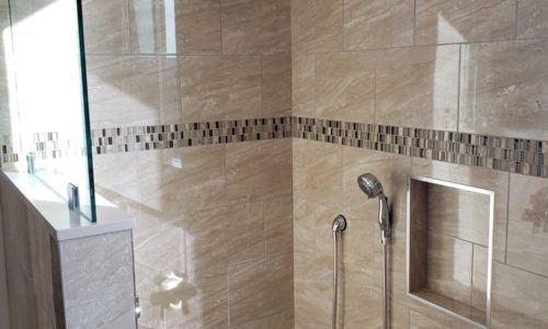 Wheelchair accessible bathroom remodel includes custom tile barrier free shower with built in bench, grab bars, hand held shower head, The vanity is wheelchair accessible.