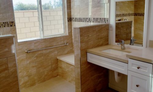 Wheelchair accessible bathroom remodel includes custom tile barrier free shower with built in bench, grab bars, hand held shower head, The vanity is wheelchair accessible.